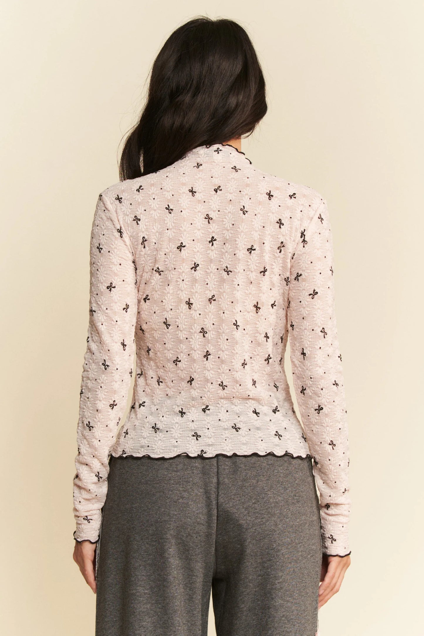 Delicate off-white knit cardigan with black floral pattern and scalloped hem