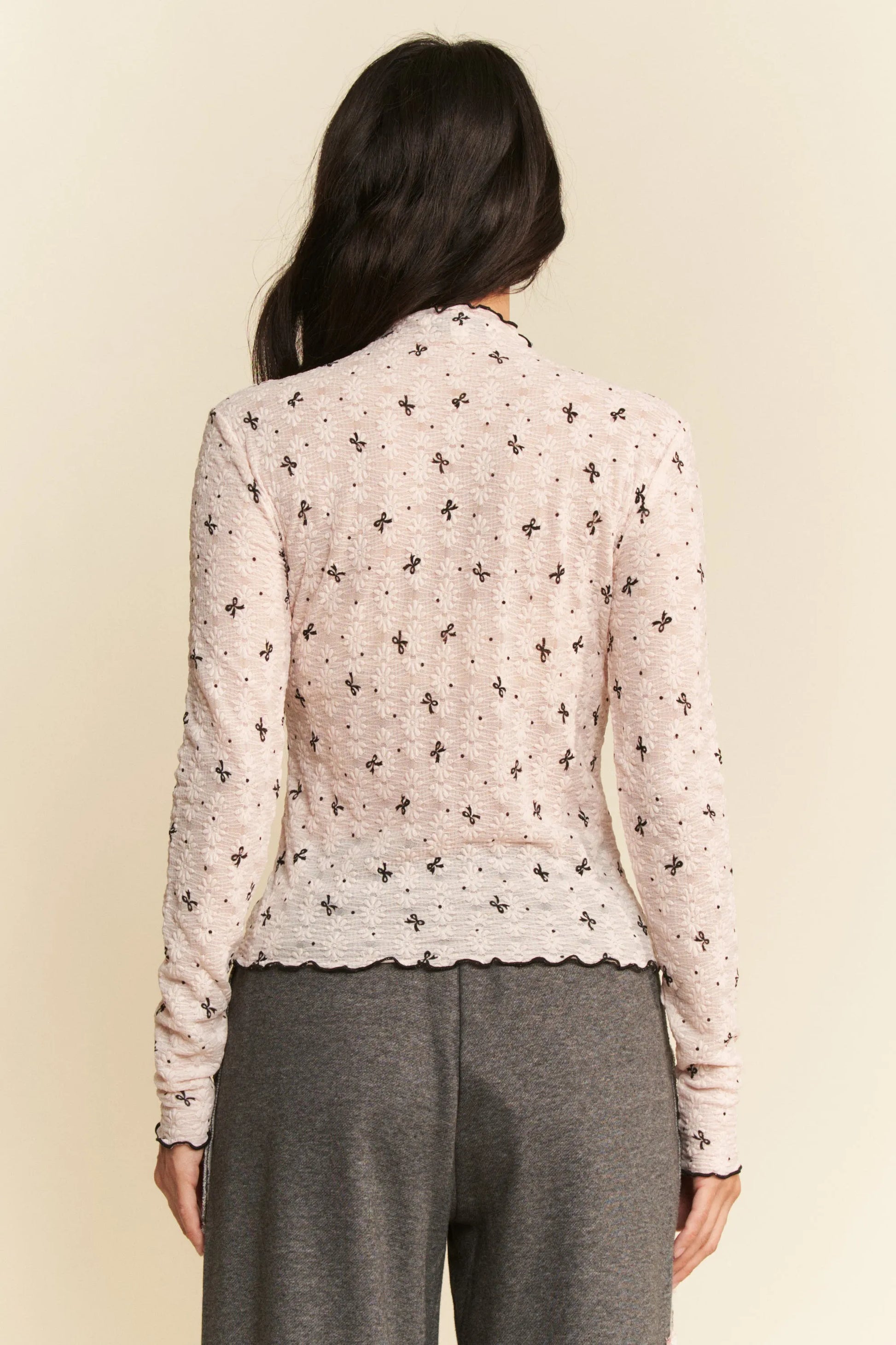 Delicate off-white knit cardigan with black floral pattern and scalloped hem
