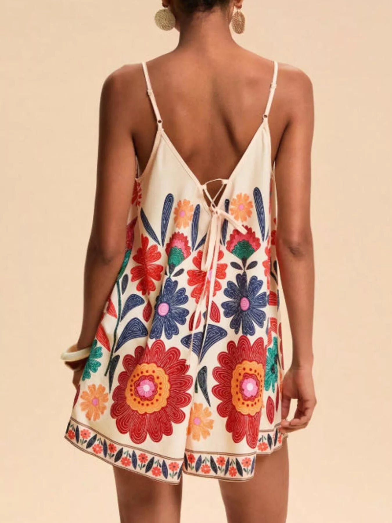 Floral print spaghetti strap romper in cream with vibrant red orange blue blossoms