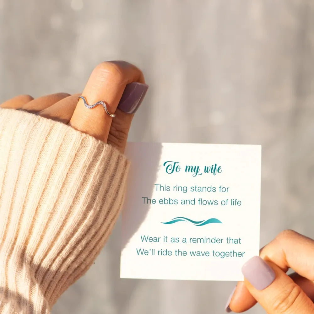 Hand wearing a wavy silver ring with a sentimental message card