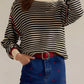 Black and white striped round neck long sleeve knit sweater with red trim