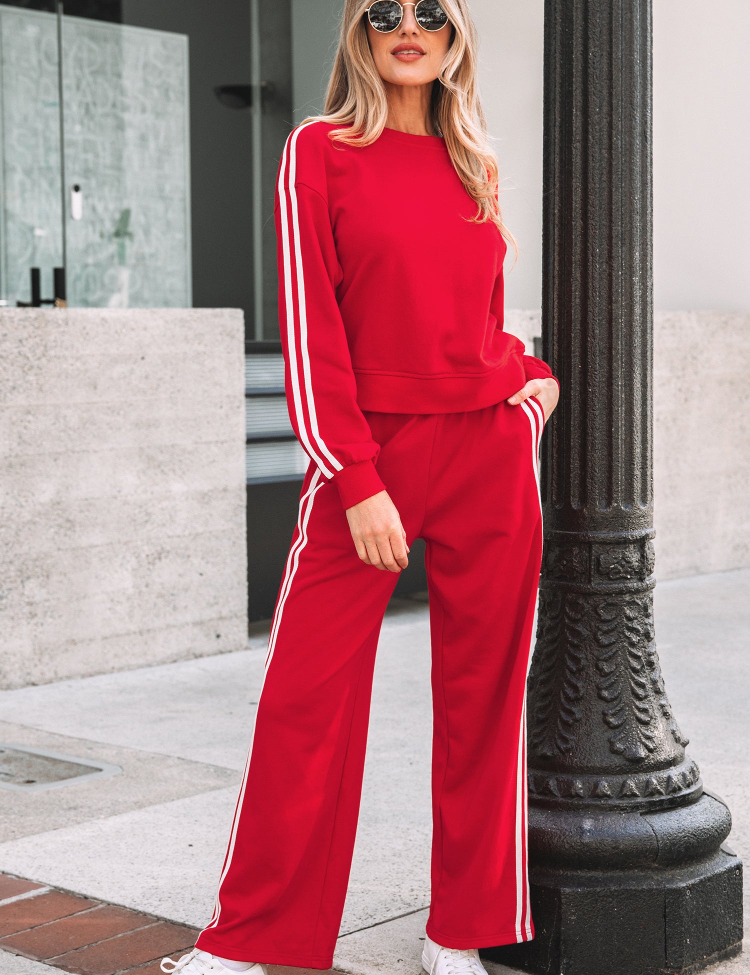 Woman wearing a red tracksuit with white stripes standing next to a black lamp post.