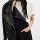 Black leather biker jacket with silver zippers on denim overalls