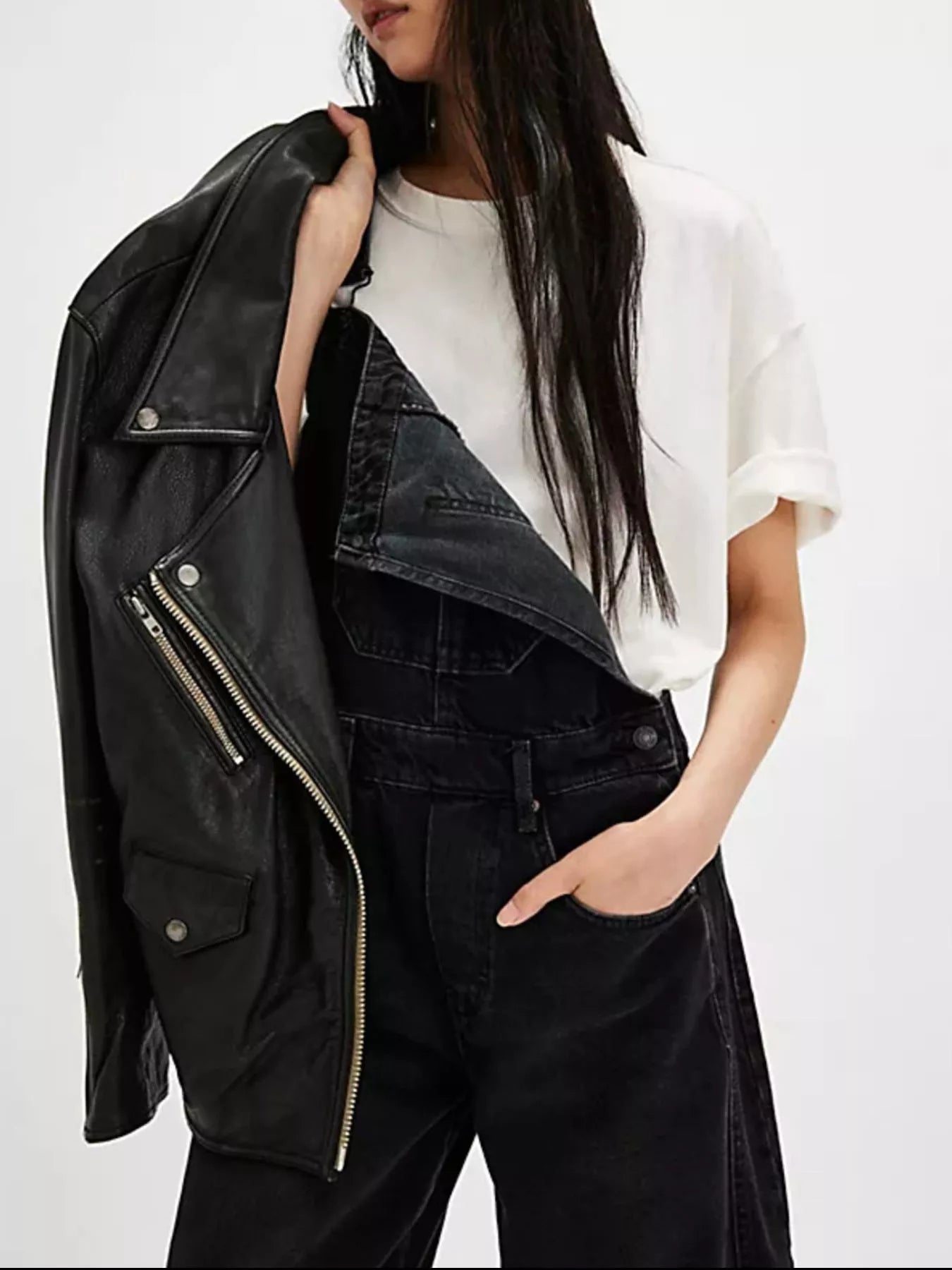 Black leather biker jacket with silver zippers on denim overalls
