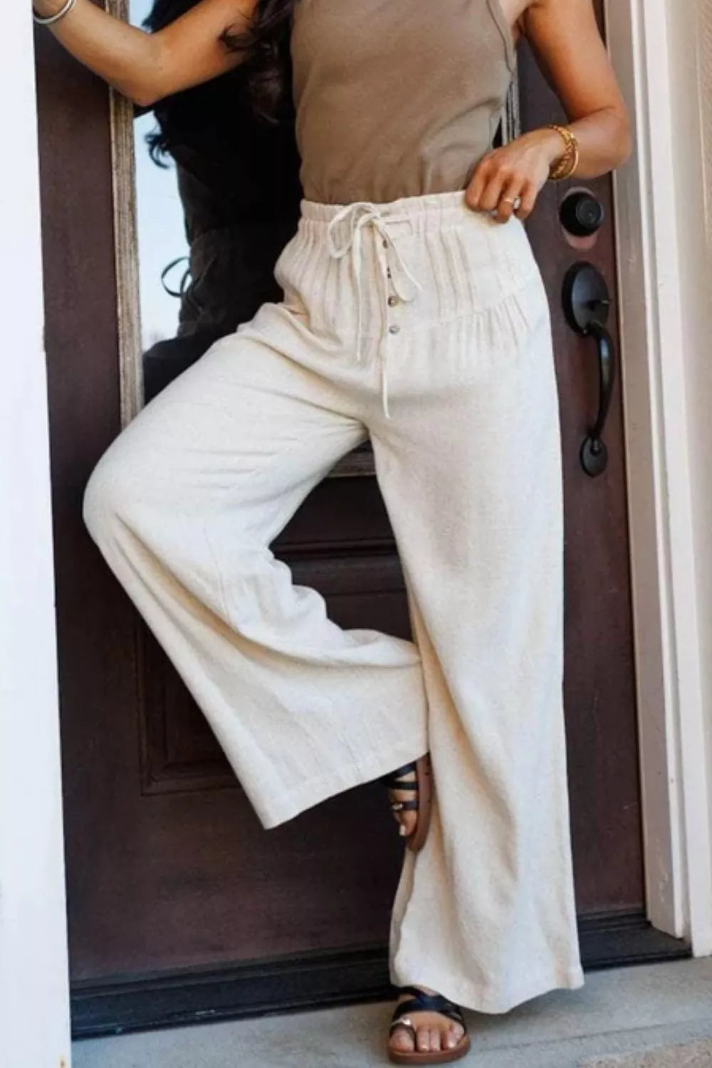 Cream-colored high-waisted wide-leg drawstring pants with button closure