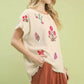 Umgee linen blend top with cream fabric, frayed edges, and vibrant floral embroidery