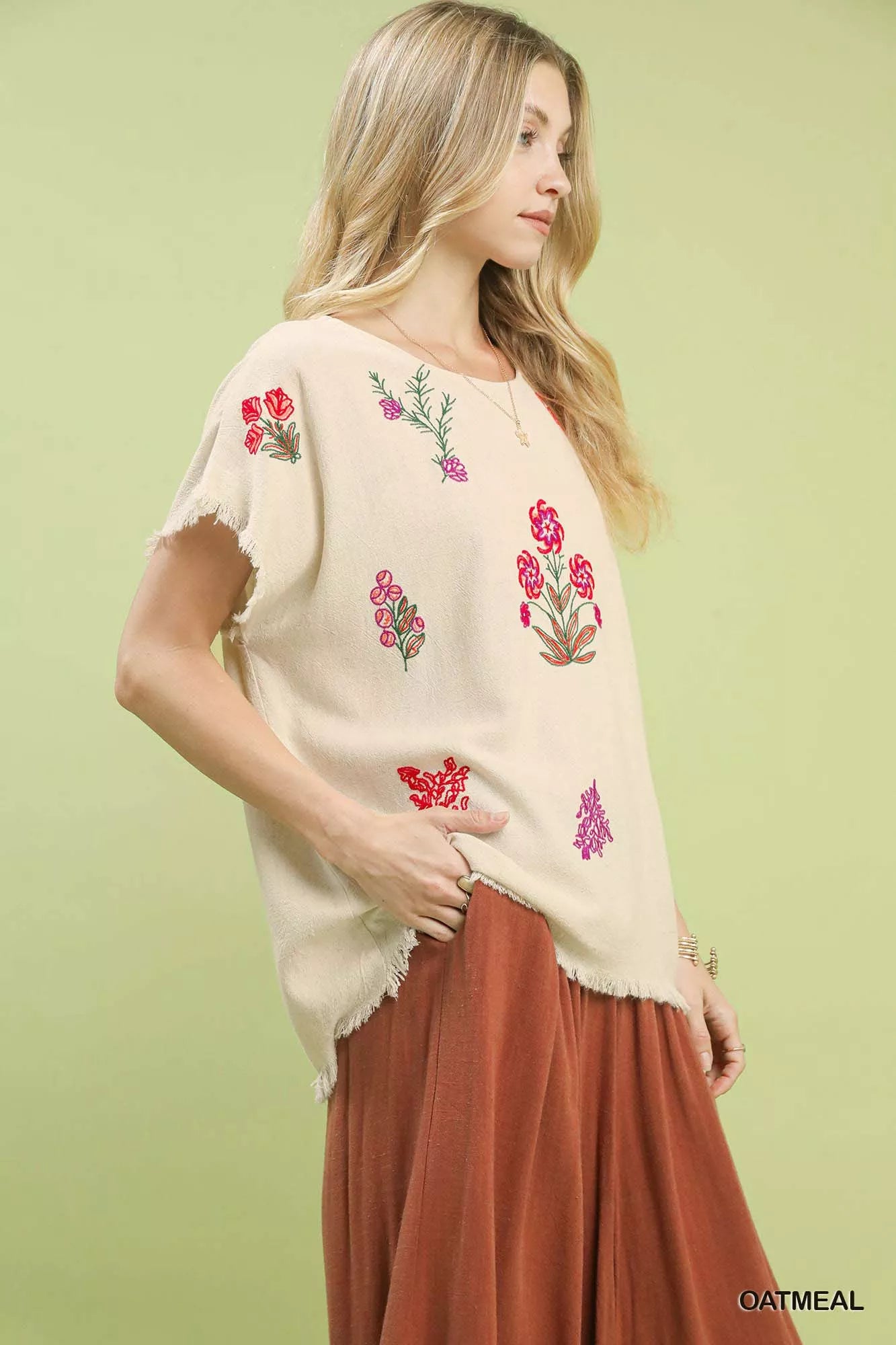 Umgee linen blend top with cream fabric, frayed edges, and vibrant floral embroidery