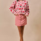 Pink sweater with red roses, hearts, and scalloped hem over SO ME denim mini skirt