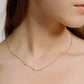 Gold necklace with a gold cross pendant and round moissanite stone worn by a person