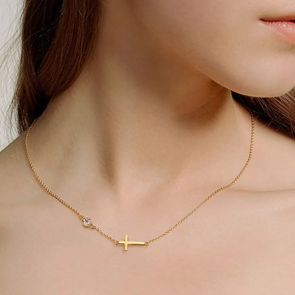 Gold necklace with a gold cross pendant and round moissanite stone worn by a person