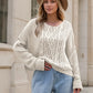 Cream-colored chunky-knit round neck sweater with cable patterns and bell sleeves
