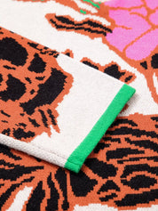 White skull towel with green trim on floral knit quarter zip sweater