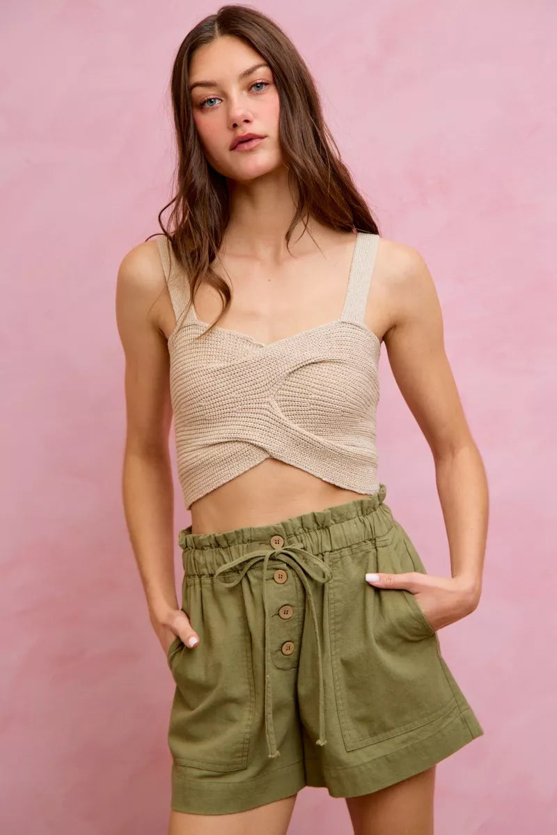 Beige crocheted crop top with thin straps over twill shorts