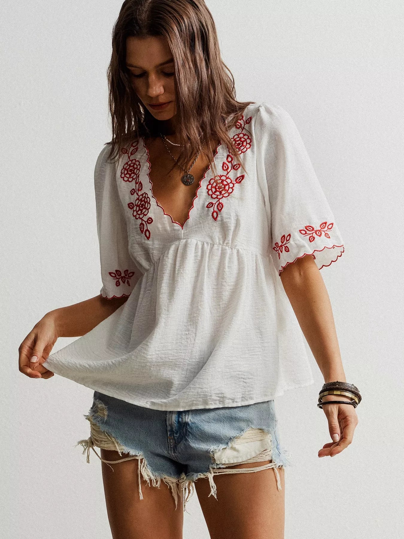 White embroidered bohemian V-neck blouse with red floral patterns and scalloped sleeves