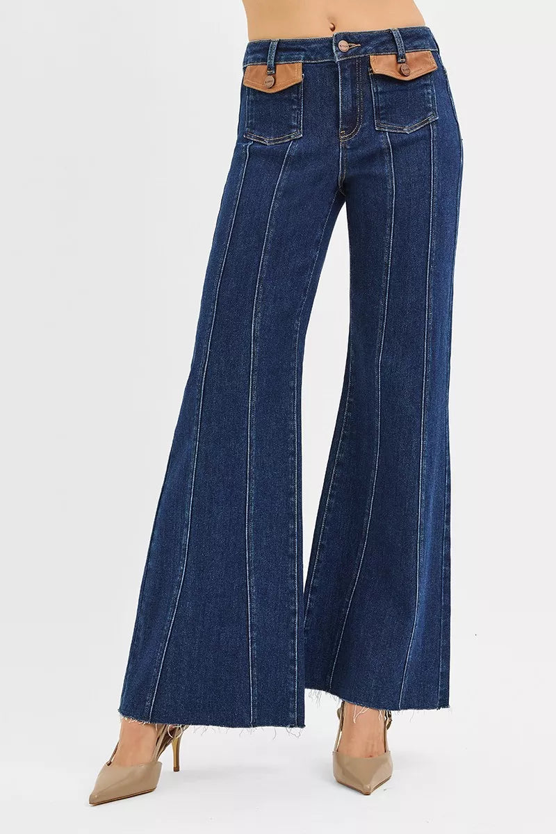 RISEN high-rise wide flare jeans in dark blue denim with tan leather flap pockets and frayed hem