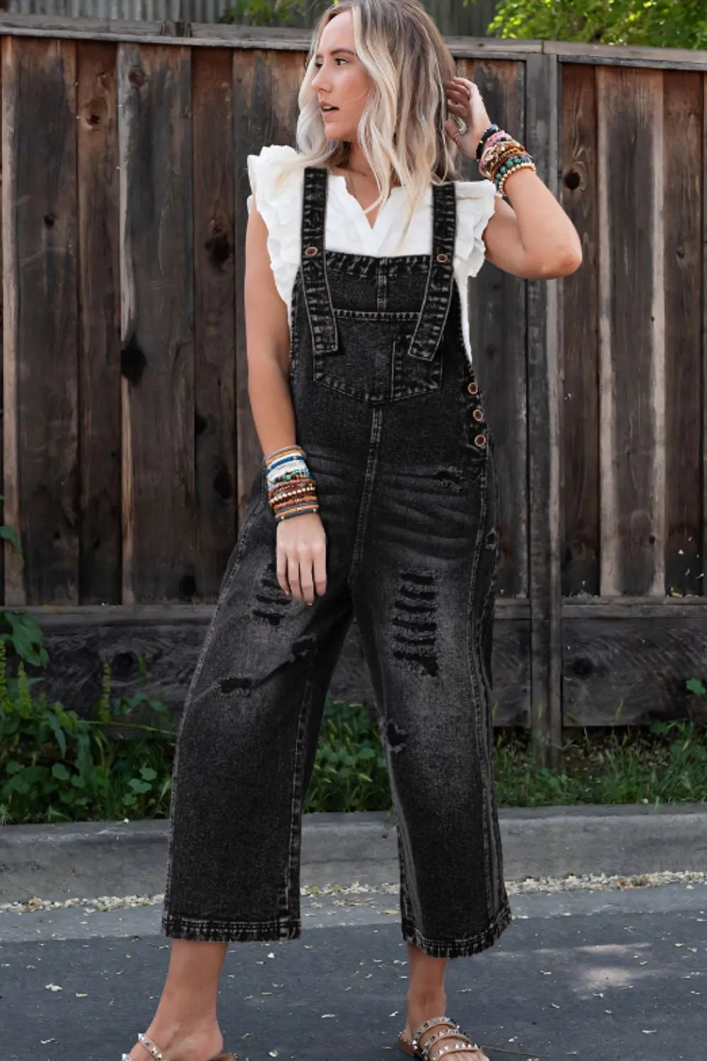 Black distressed wide-leg denim overalls with frayed hem, back view