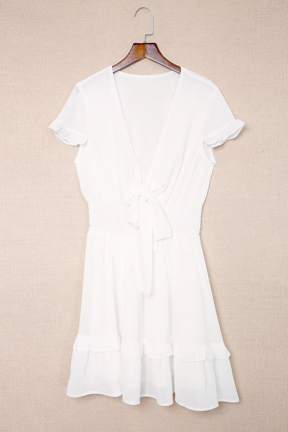 White tie-front mini dress with smocked waist, v-neck and ruffled hem