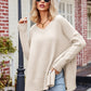Beige v-neck oversized knit sweater with ribbed cuffs and exposed seams