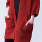 Woman wearing a cozy, rust-red Chunky Knit Open Front Cardigan with a textured waffle weave and deep front pockets, styled over a black outfit.