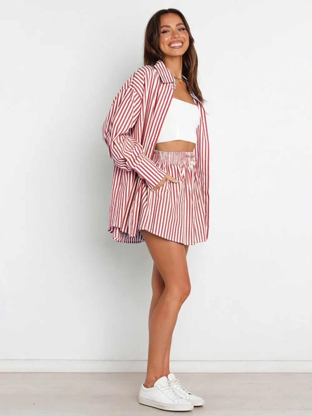 Woman in red white striped dropped shoulder shirt shorts set with sneakers