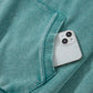 White iPhone 13 peeking from pocket of teal mineral wash hoodie