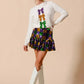 White long-sleeved sweater with Mardi Gras purple, gold, green sequined bows