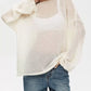 Cream-colored sheer knit boat neck dropped shoulder sweater with loose fit and voluminous sleeves