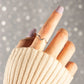 A woman's index finger wearing a wavy silver ring with cz accents