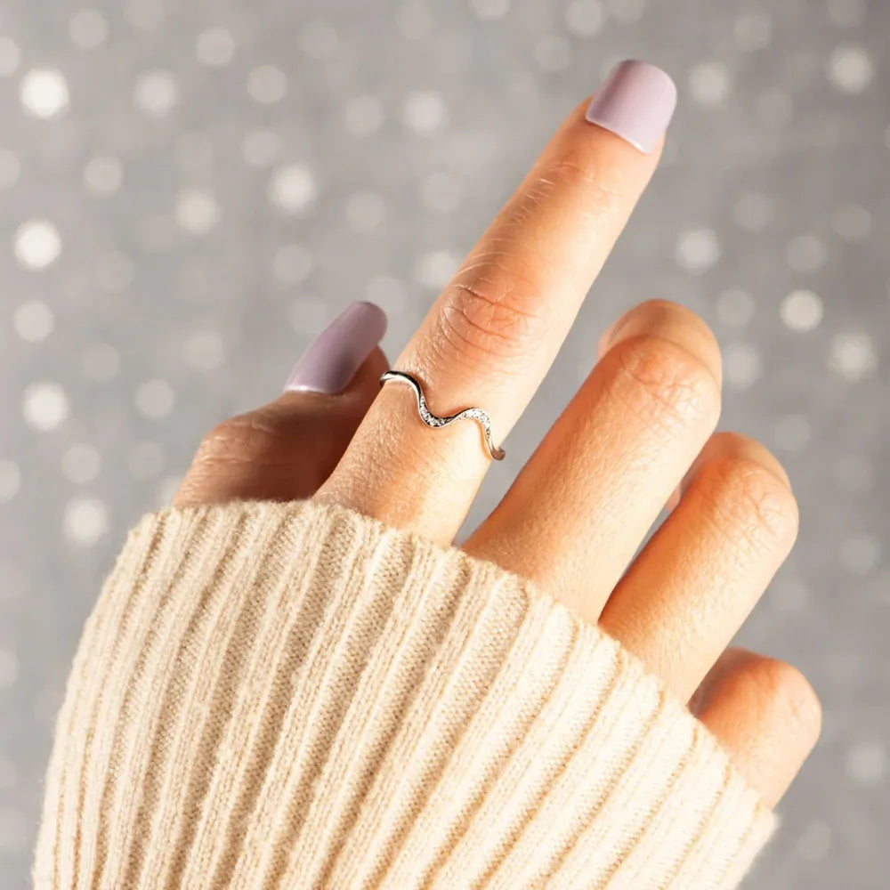A woman's index finger wearing a wavy silver ring with cz accents