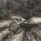 Silver wave-shaped ring on a textured stone surface