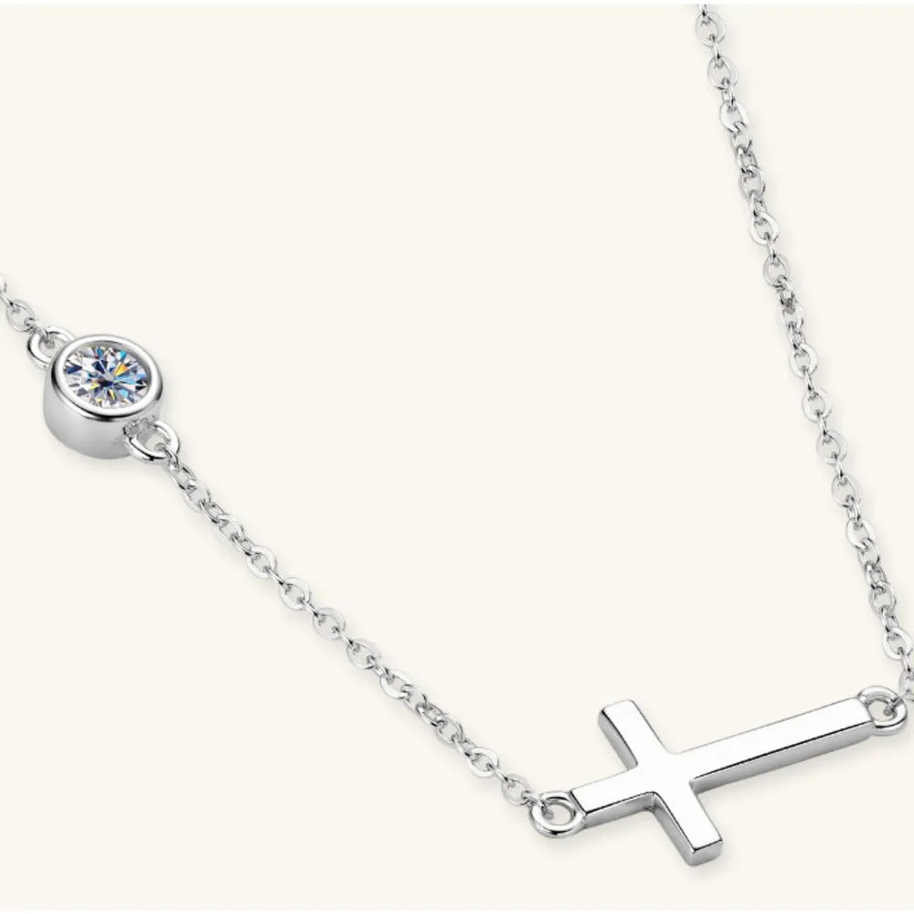 Silver necklace with a cross pendant and round gemstone on a white background