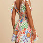 Daverri V-neck smocked waist mini dress with vibrant sun, checker, swirl print