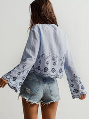 Light blue floral embroidered tie-front blouse with bell sleeves and denim shorts