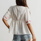 White embroidered floral V-neck blouse with red patterns on sleeves