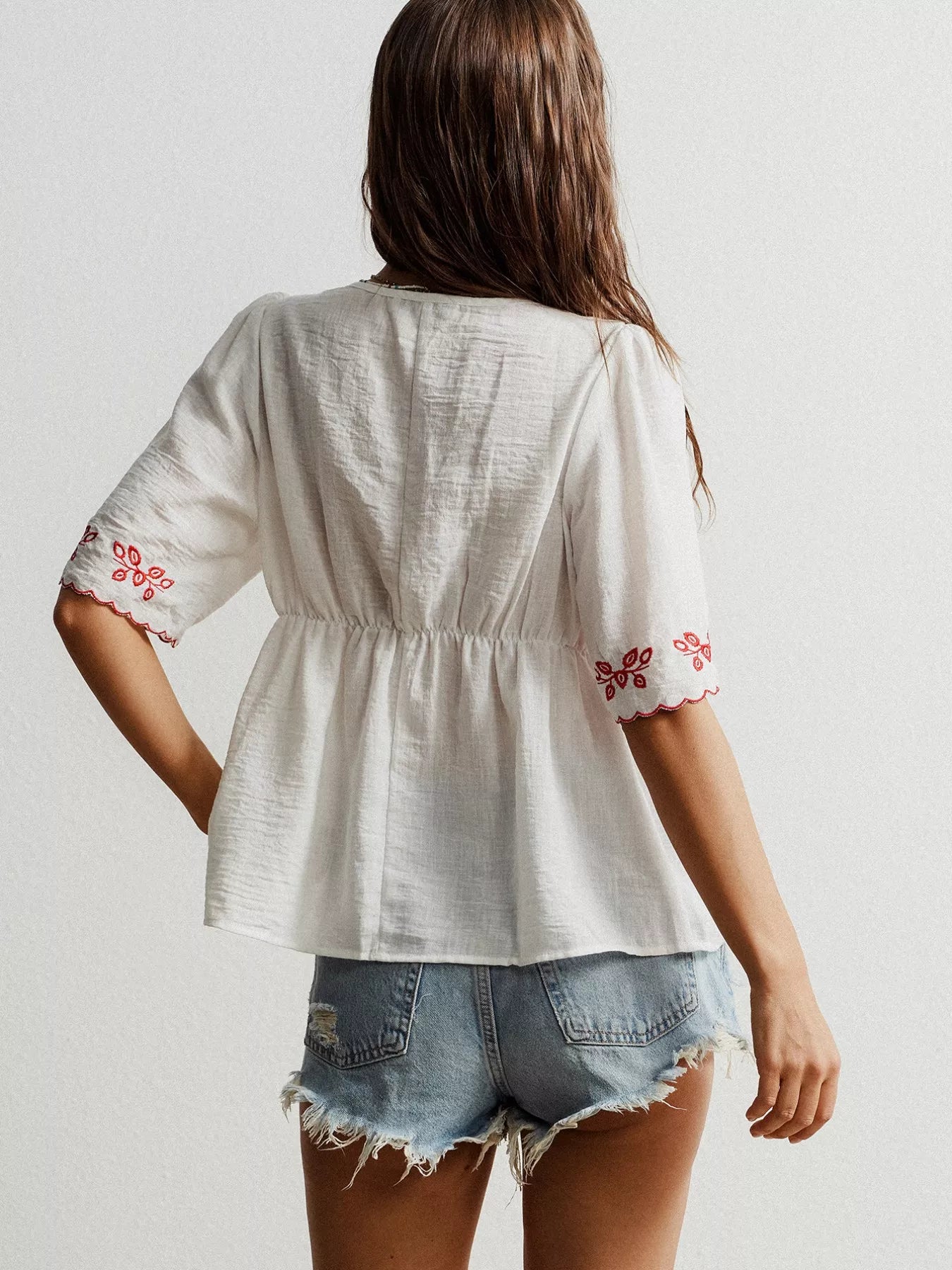 White embroidered floral V-neck blouse with red patterns on sleeves