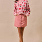Pink floral knit sweater with red roses and hearts paired with SO ME vintage wash scallop edge denim mini skirt