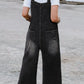 Distressed wide strap denim overalls in dark gray with wide legs and distressed pockets
