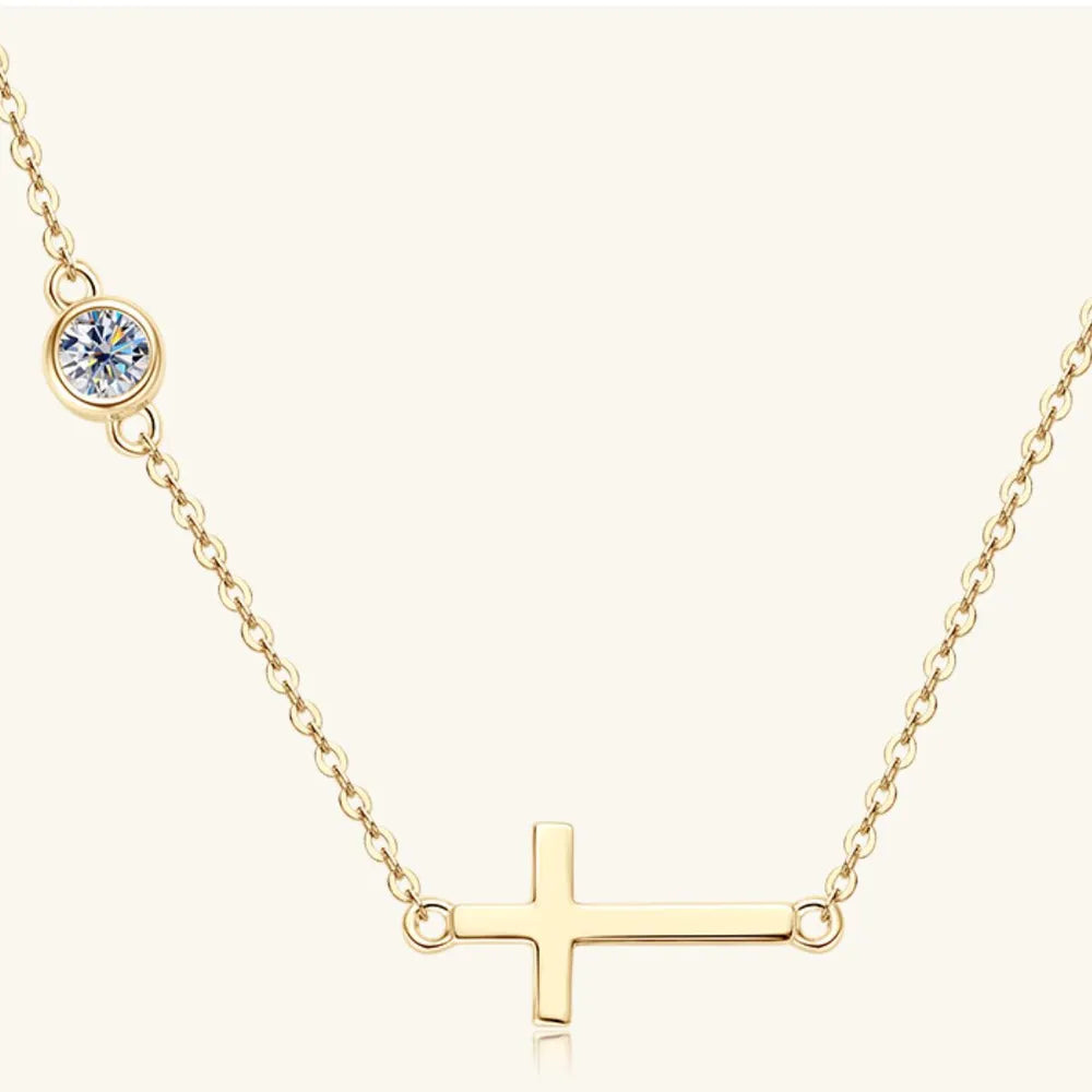 Gold necklace with a small round moissanite stone and a gold horizontal cross pendant on a white background