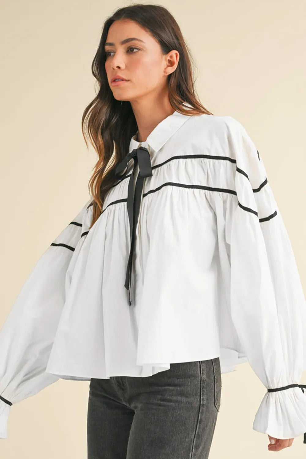 White blouse with black trim, bowtie collar, and flounce sleeves