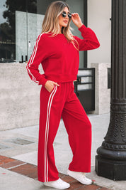 Woman wearing a red tracksuit with white stripes outdoors.