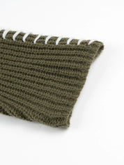 Olive green textured knit scarf with white cord accents on sweater