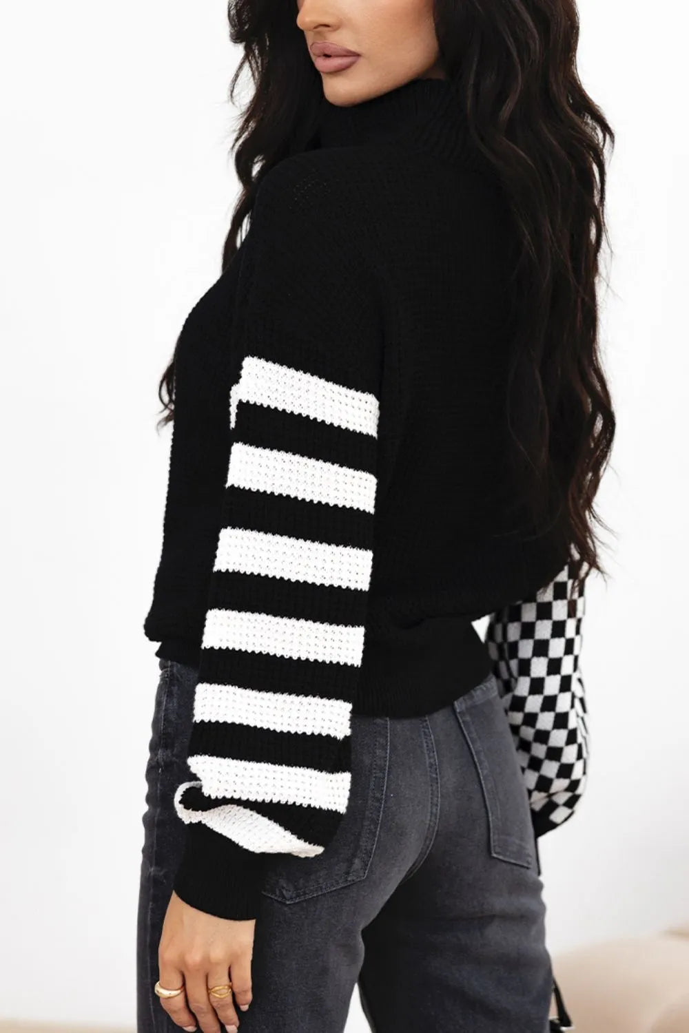 Black knit turtleneck sweater with white striped sleeves and dropped shoulders