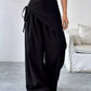 Daverri Wrap-Front Wide-Leg Pants in black with draped asymmetrical design and side tie detail