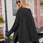 Black knit V-neck poncho with slit exposed seams, ribbed cuffs and hem