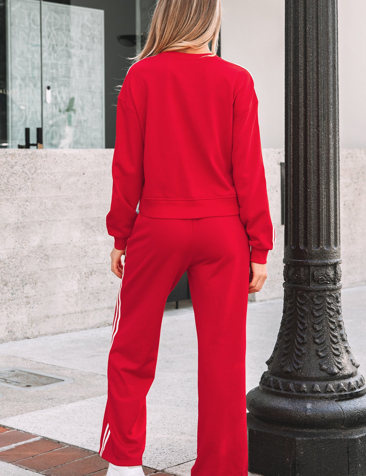 Person wearing a red tracksuit standing next to a black lamp post.