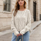 Cream-colored chunky-knit cable sweater with round neck and dropped shoulders