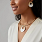 Gold-toned necklace with a white, circular pendant featuring an intricate gold pattern around its edge.