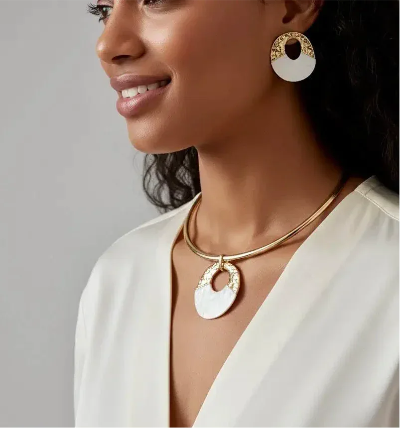 Gold-toned necklace with a white, circular pendant featuring an intricate gold pattern around its edge.
