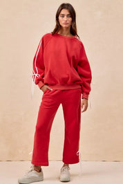 Red drawstring track pants with white laces, pockets, and BiBi bow details