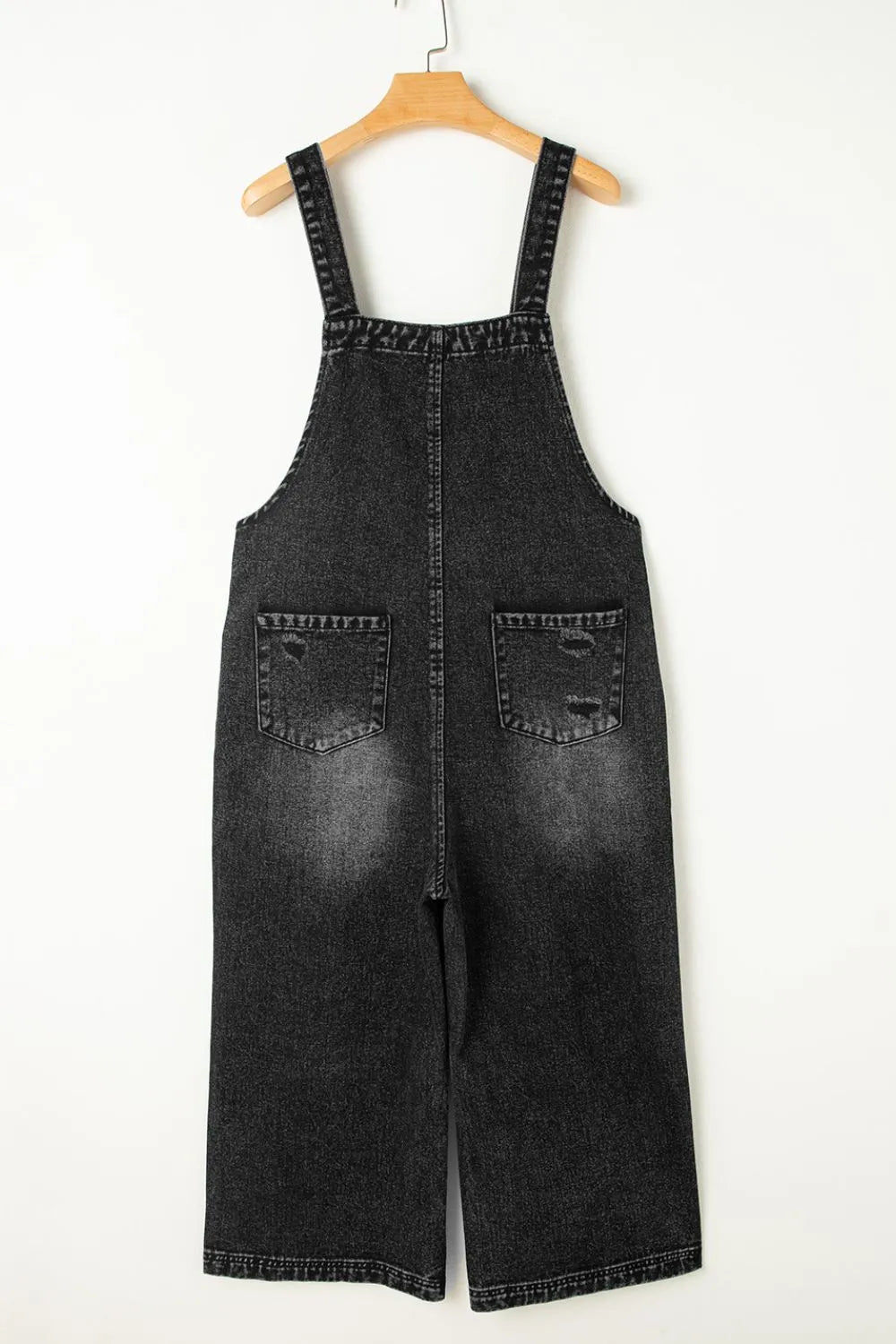 Distressed wide strap denim overalls with faded wash and distressed pockets